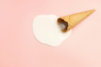 Photo of Melted ice cream and wafer cone on light pink background, top view. Space for text