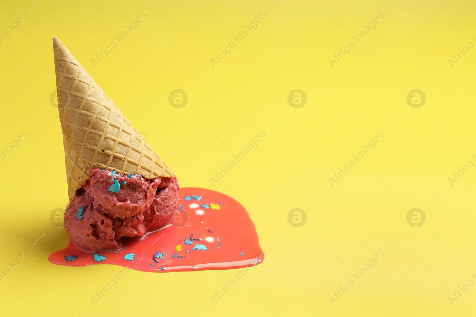 Photo of Melted ice cream in wafer cone on yellow background. Space for text