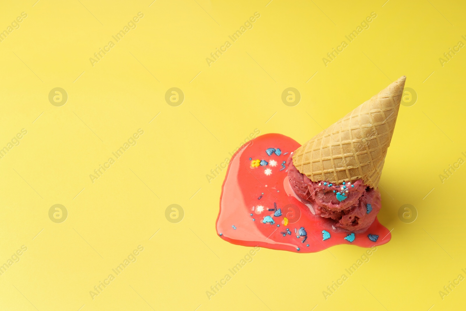 Photo of Melted ice cream in wafer cone on yellow background. Space for text