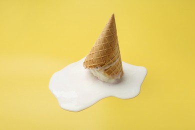 Photo of Melted ice cream in wafer cone on yellow background