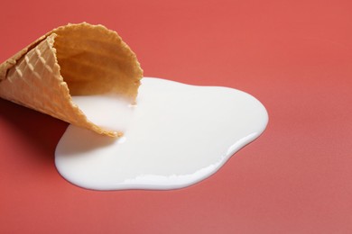 Photo of Melted ice cream and wafer cone on pale pink background, closeup. Space for text