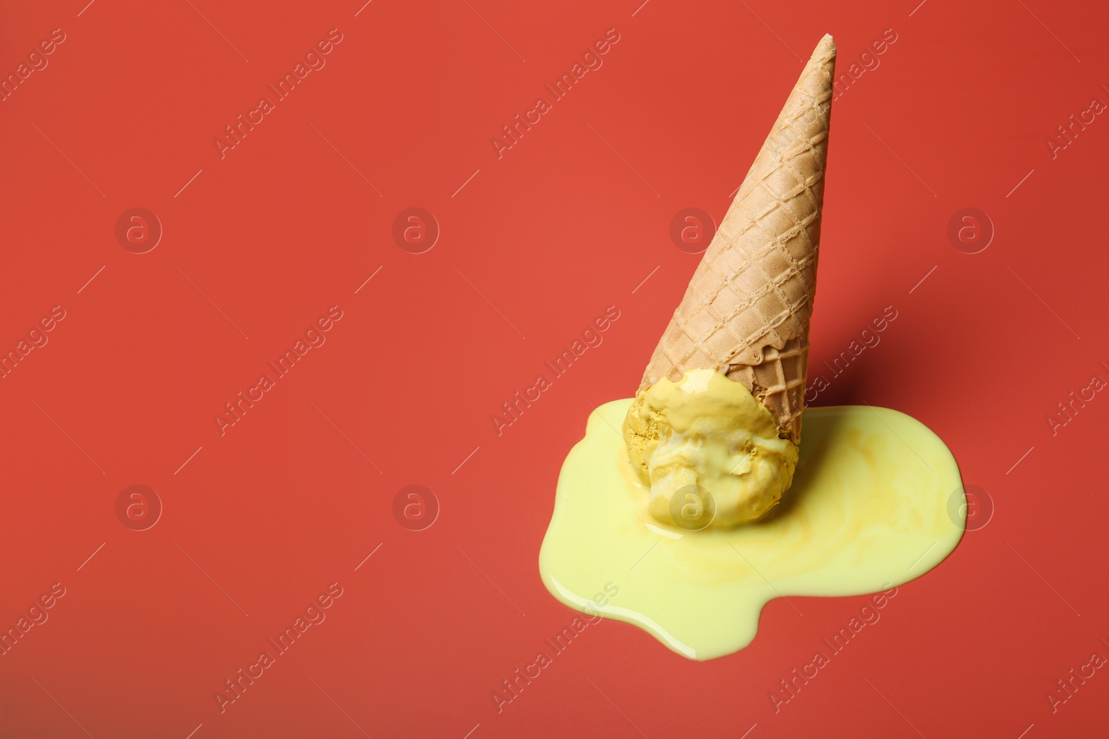 Photo of Melted ice cream in wafer cone on pale pink background. Space for text