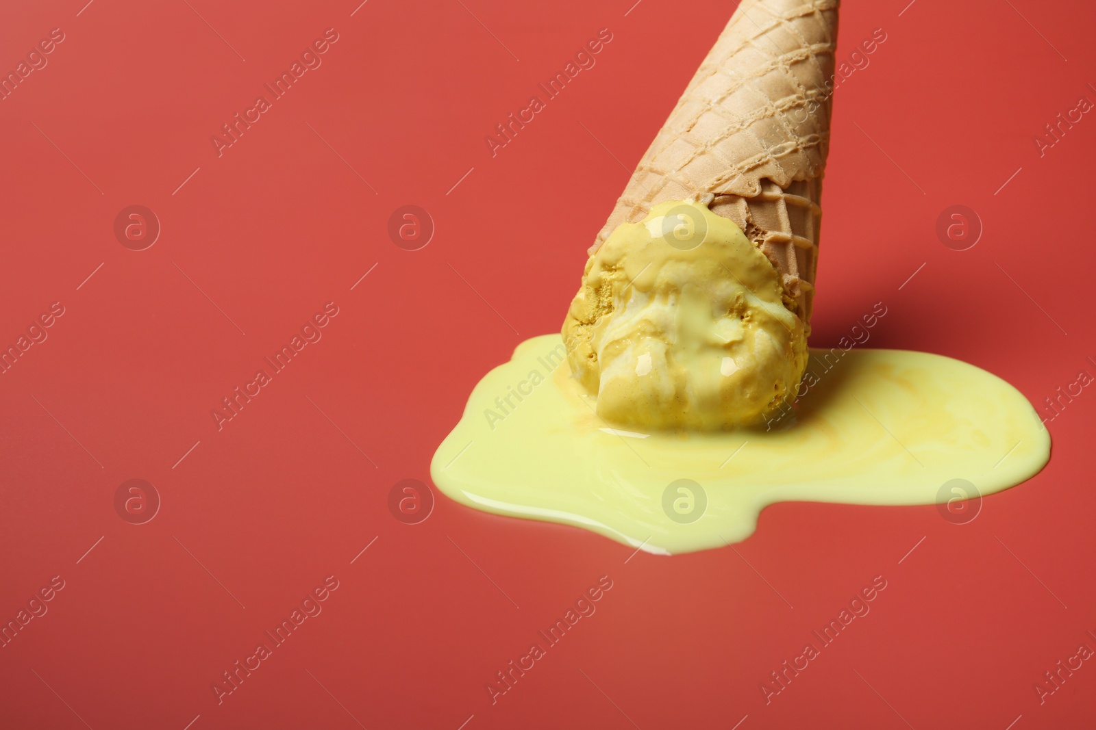 Photo of Melted ice cream in wafer cone on pale pink background. Space for text