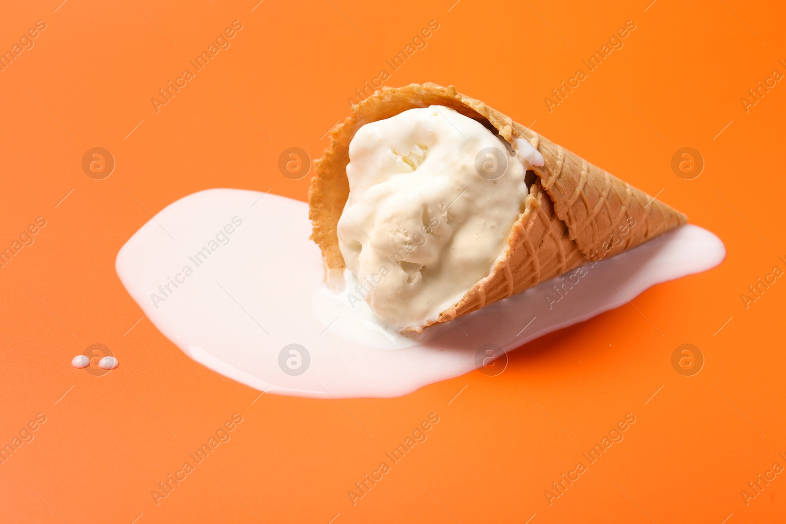 Photo of Melted ice cream in wafer cone on orange background