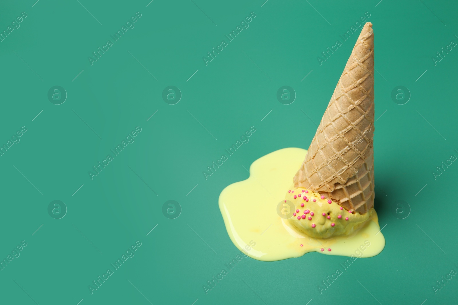 Photo of Melted ice cream in wafer cone on pale green background. Space for text