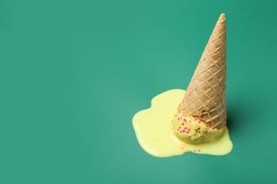 Photo of Melted ice cream in wafer cone on pale green background. Space for text