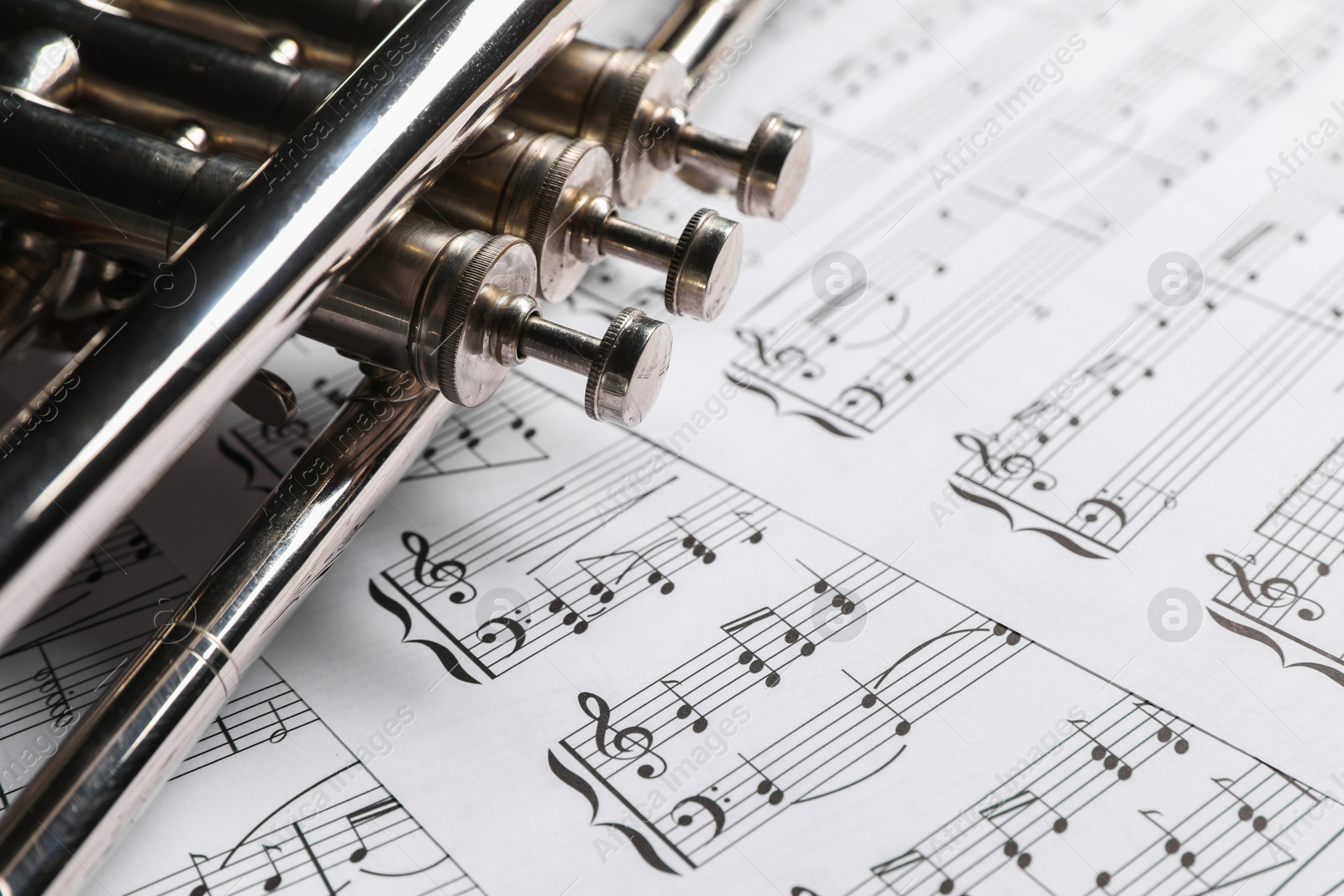 Photo of Trumpet on music sheet papers with notes, closeup