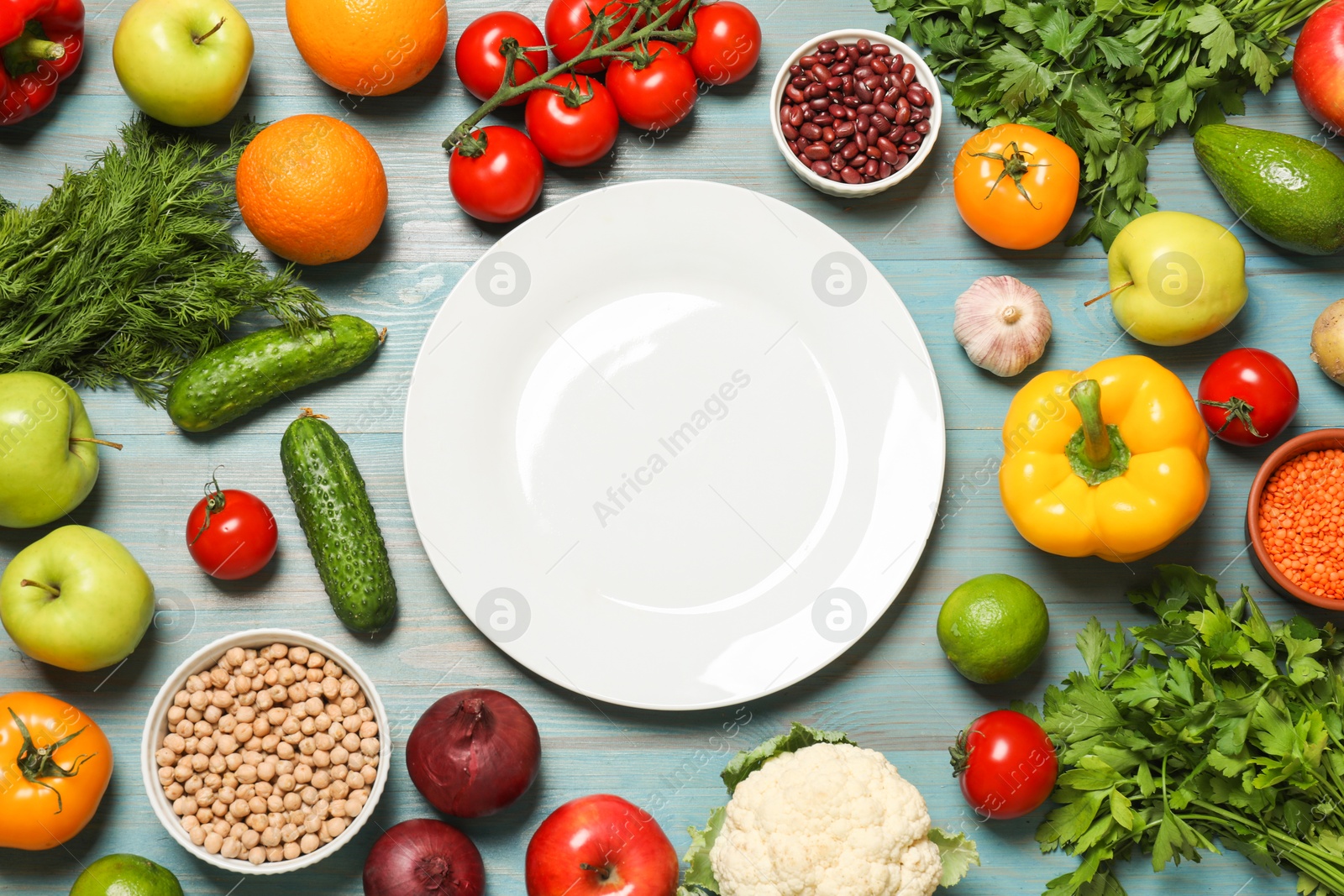 Photo of Different vegetarian products and plate on light blue wooden table, top view