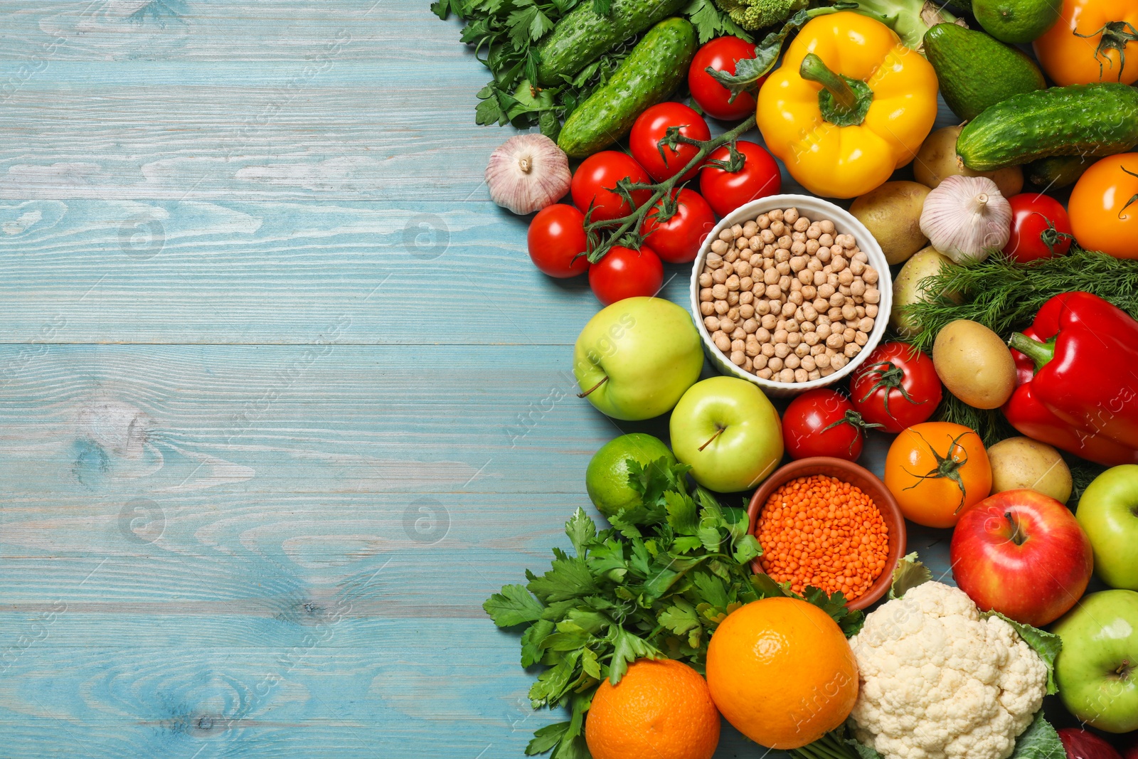 Photo of Different vegetarian products on light blue wooden table, top view. Space for text