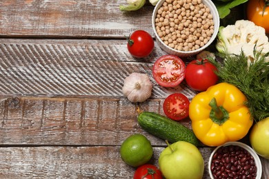 Photo of Different vegetarian products on wooden table, top view. Space for text