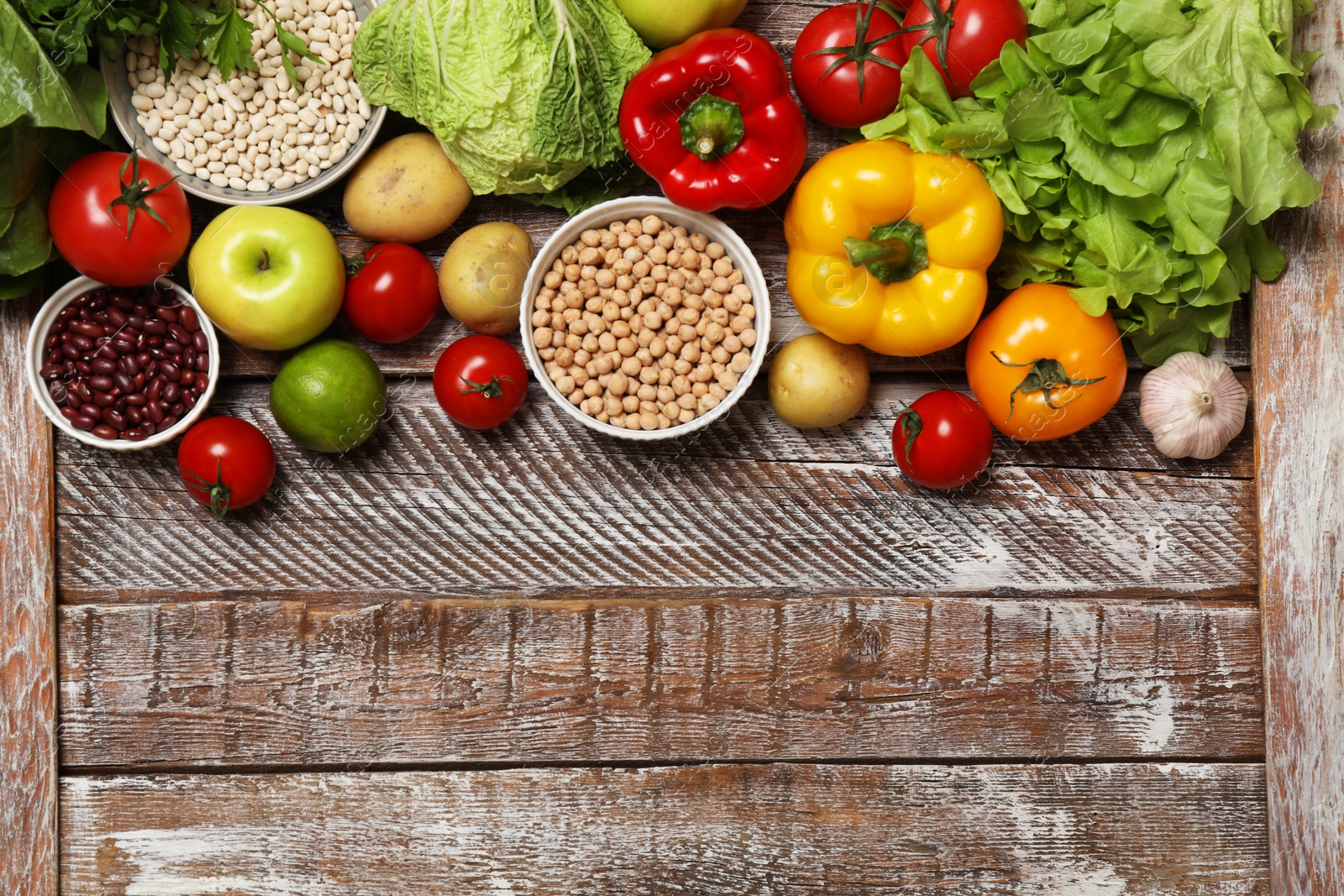 Photo of Different vegetarian products on wooden table, top view. Space for text