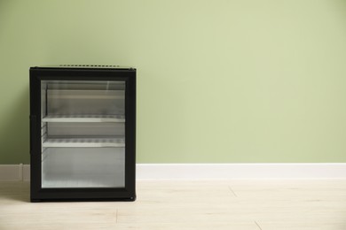 Photo of Empty modern mini refrigerator near olive wall, space for text