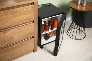 Mini refrigerator with different drinks and snacks indoors