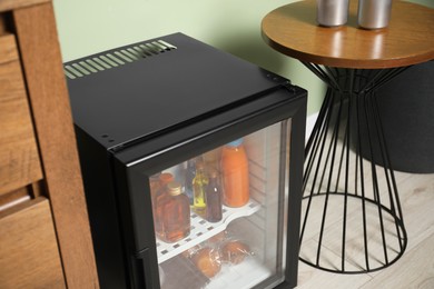 Mini refrigerator with different drinks and snacks indoors