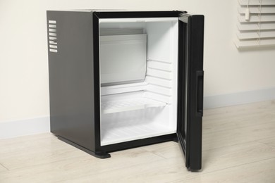 Photo of Empty modern mini refrigerator near white wall