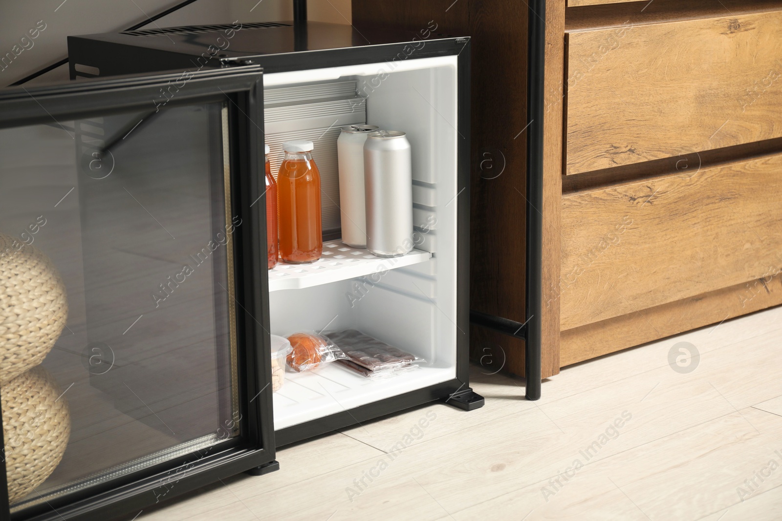 Photo of Mini refrigerator with different drinks and snacks indoors