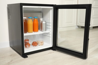 Mini refrigerator with different drinks and snacks indoors