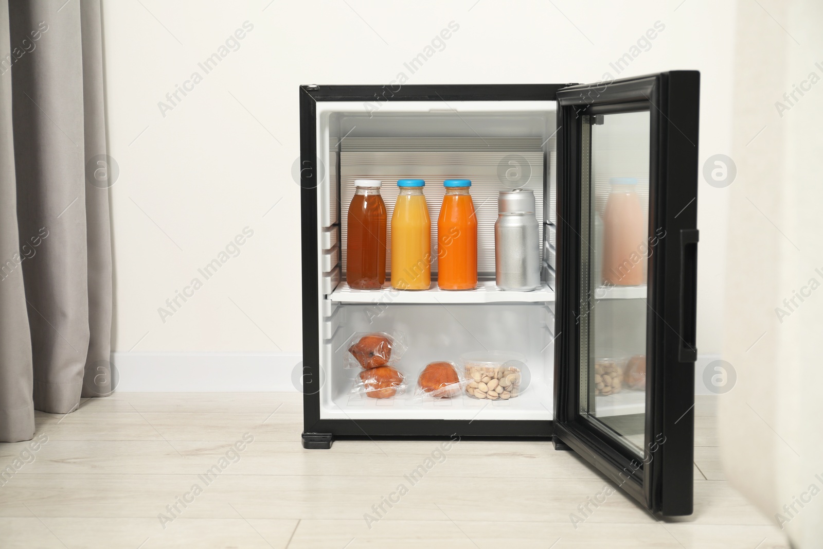 Photo of Mini refrigerator with different drinks and snacks indoors