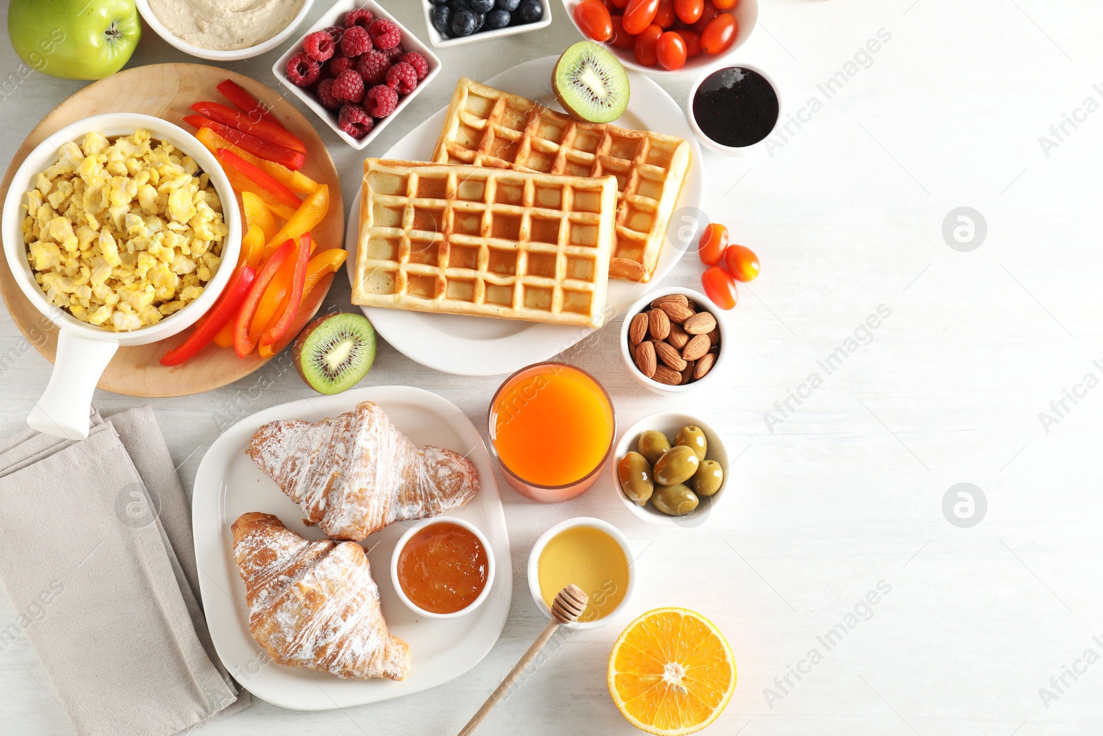 Photo of Tasty breakfast. Flat lay composition with many different food and juice on light wooden table. Space for text