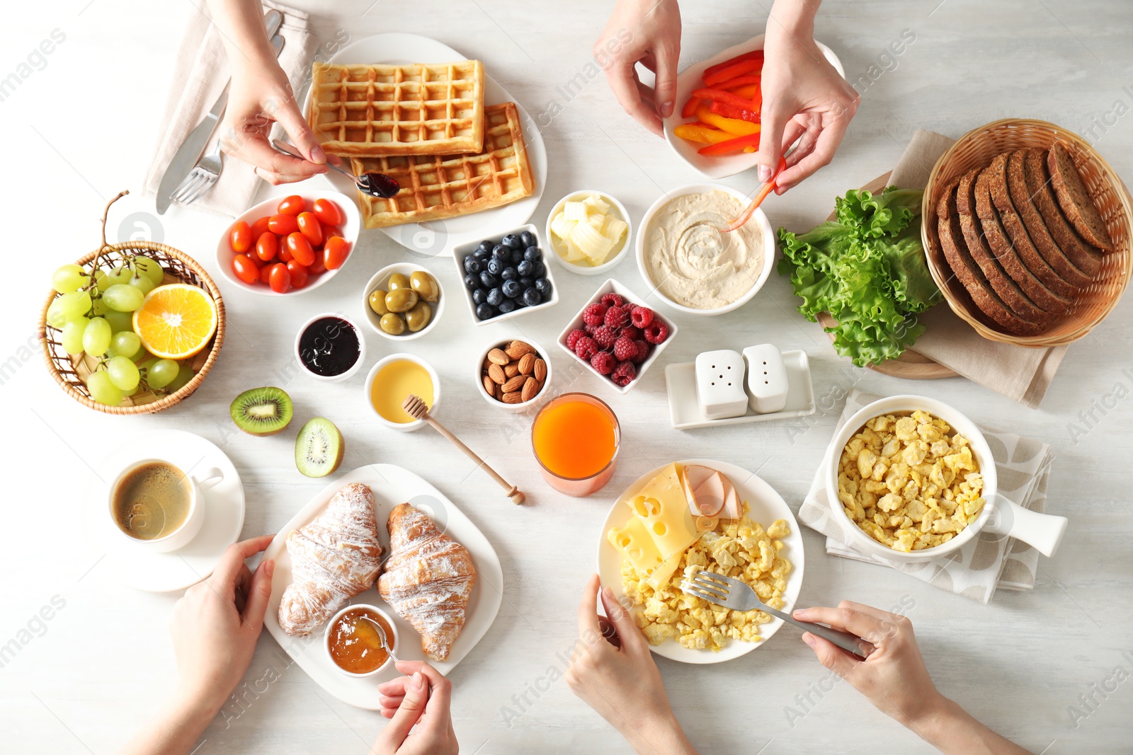 Photo of Women having tasty breakfast at light wooden table, top view