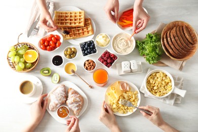 Women having tasty breakfast at light wooden table, top view