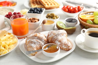 Tasty breakfast. Croissants, jam, coffee and other food on light table, closeup