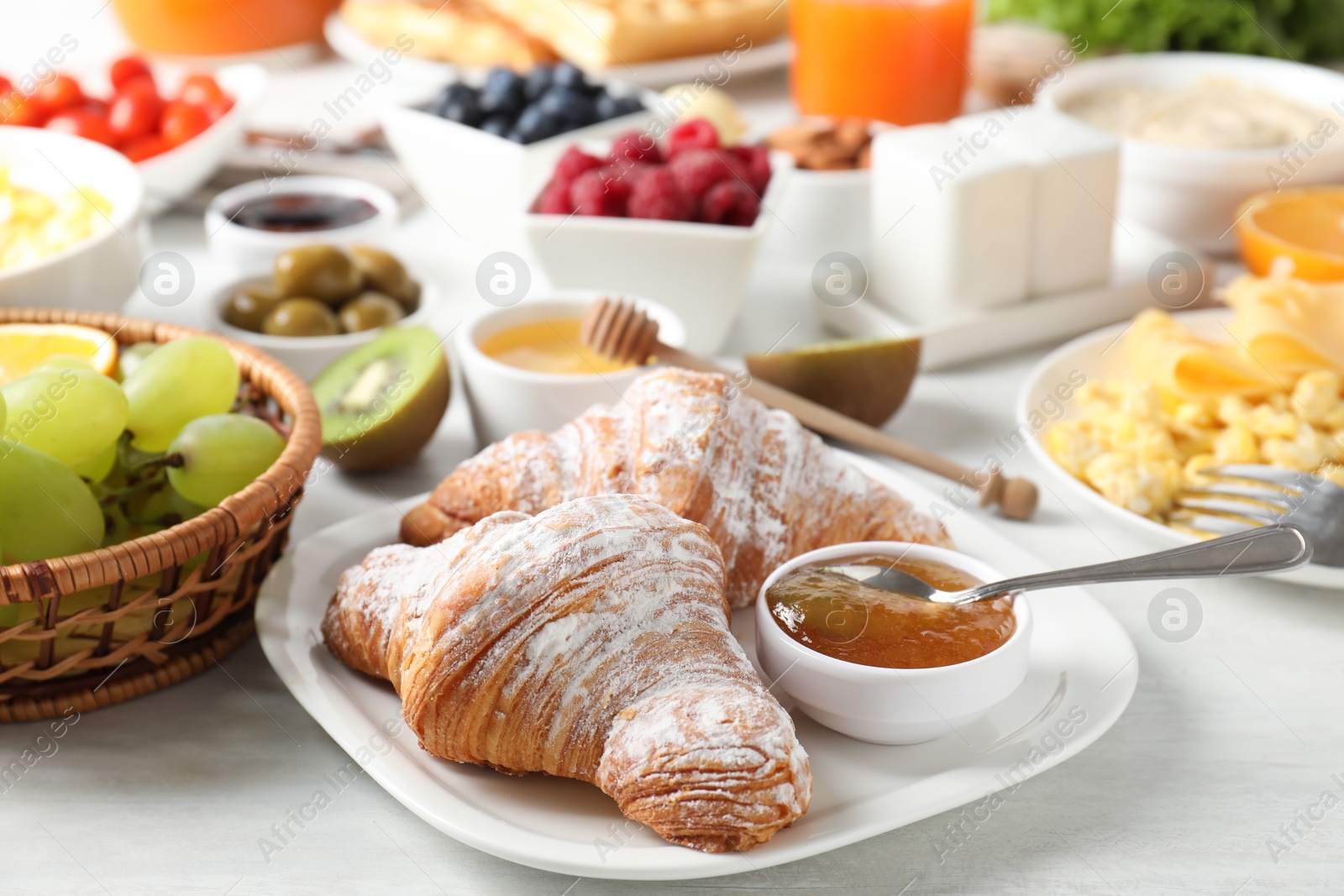 Photo of Tasty breakfast. Croissants, jam and other food on light table, closeup