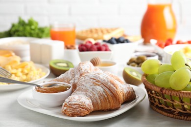 Tasty breakfast. Croissants, jam and other food on light table, closeup