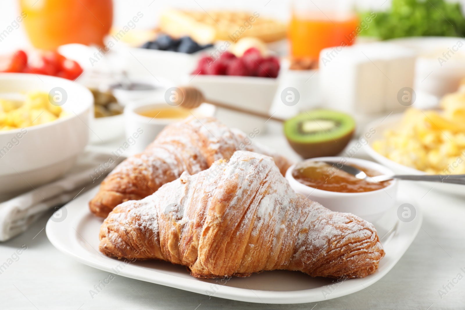 Photo of Tasty breakfast. Croissants, jam and other food on light table, closeup