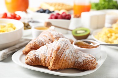 Tasty breakfast. Croissants, jam and other food on light table, closeup