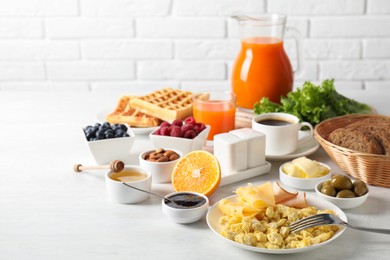 Photo of Tasty breakfast. Scrambled eggs, ham, cheese and other food served on light table