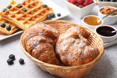 Photo of Tasty breakfast. Croissants and other food on grey textured table, closeup