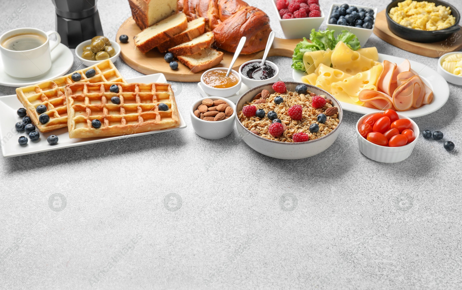 Photo of Tasty breakfast. Granola with berries and other food on grey textured table. Space for text