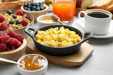 Photo of Tasty breakfast. Scrambled eggs, coffee, jam and other food on grey textured table, closeup