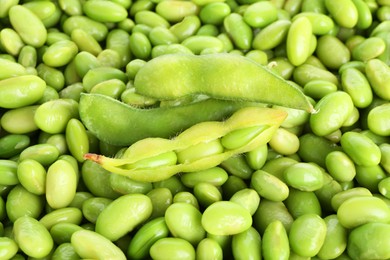 Photo of Raw green edamame pods on soybeans as background, closeup