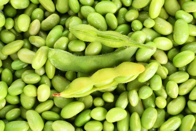 Photo of Raw green edamame pods on soybeans as background, top view