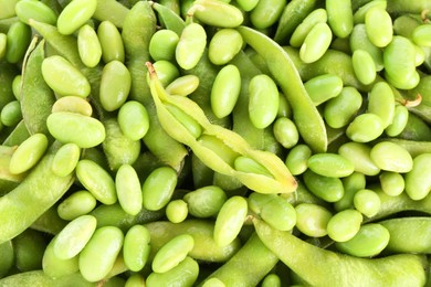 Photo of Raw green edamame pods on soybeans as background, closeup