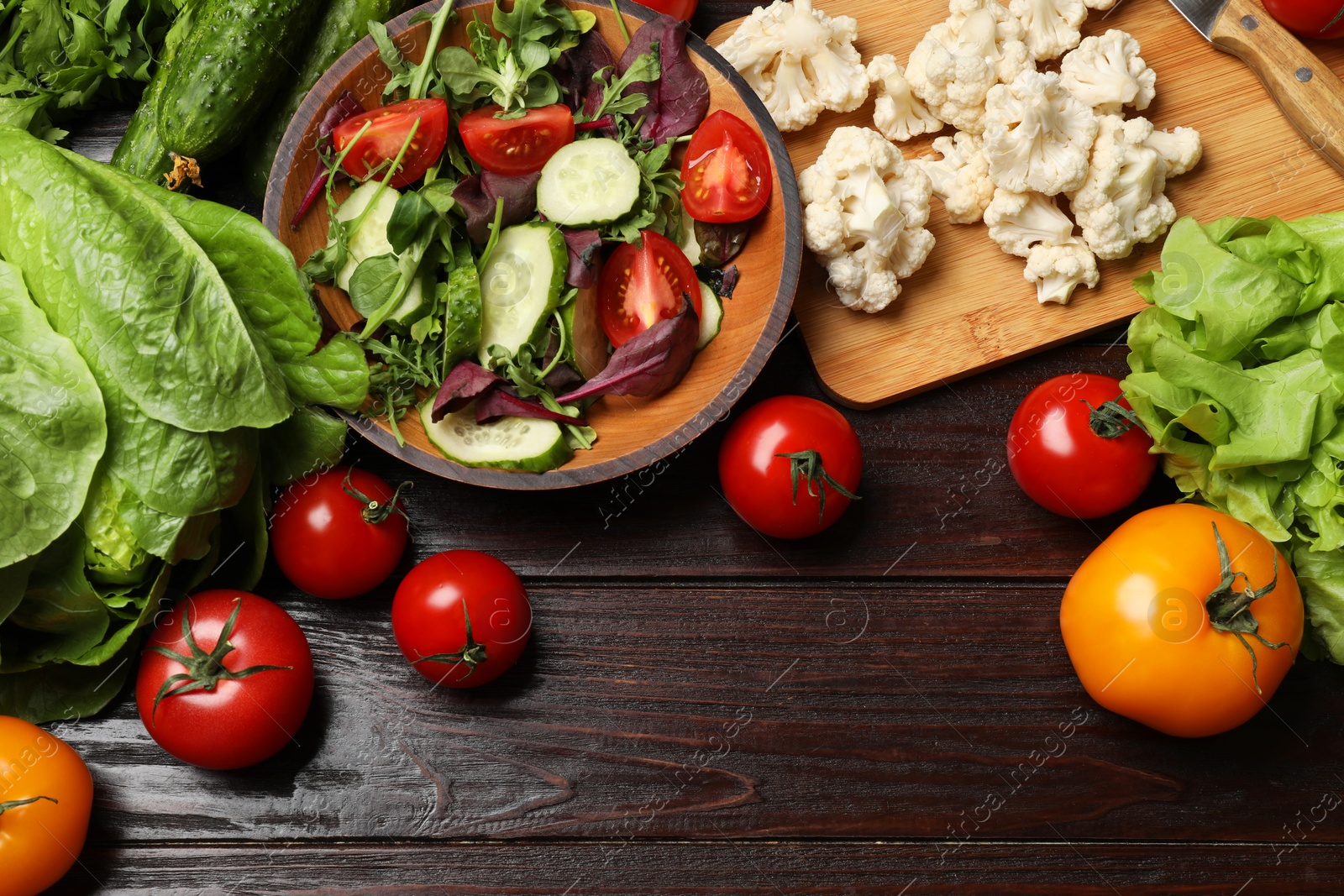 Photo of Healthy vegetarian food. Salad in bowl and vegetables on wooden table, flat lay. Space for text