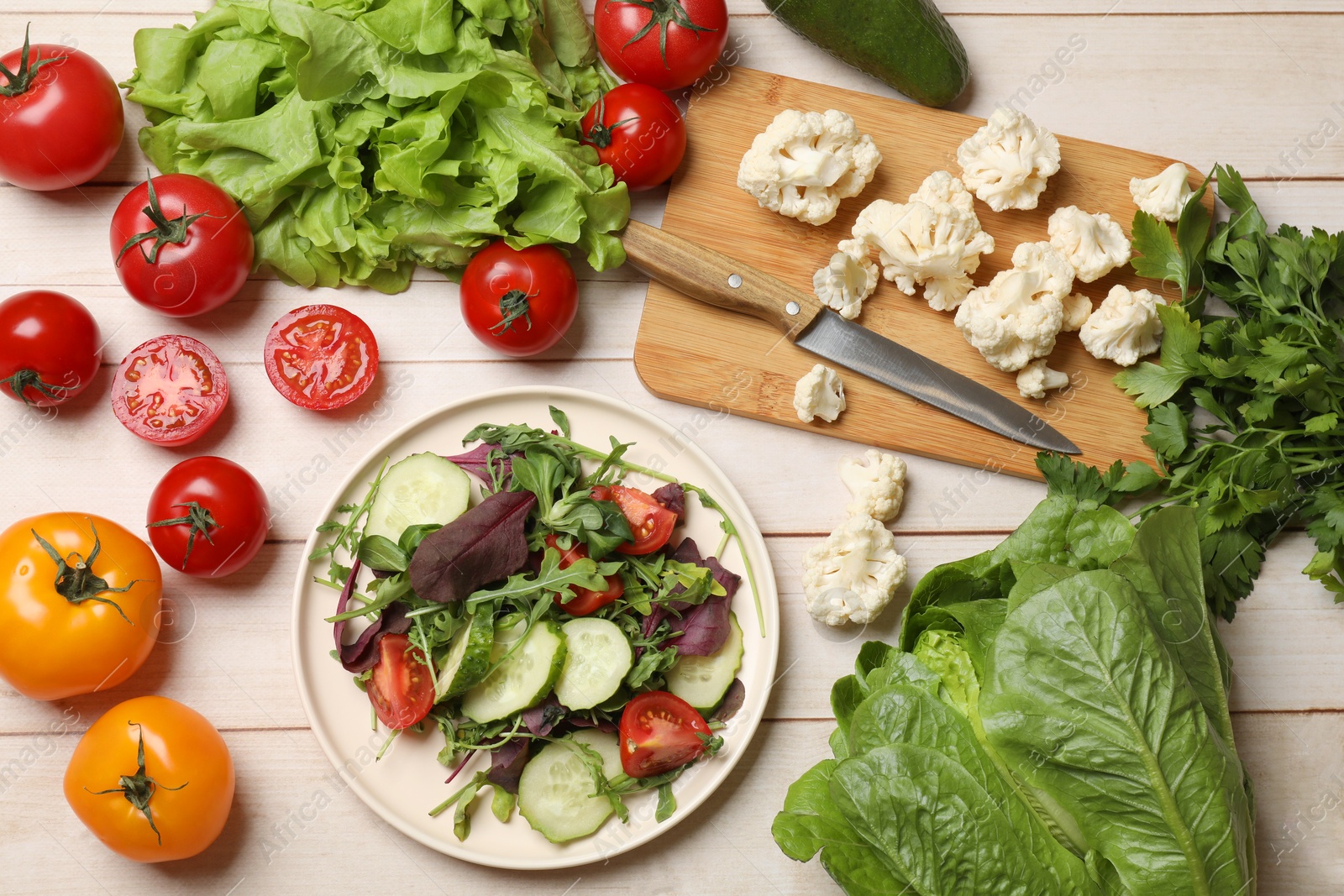 Photo of Healthy vegetarian food. Plate of salad and vegetables on light wooden table, flat lay