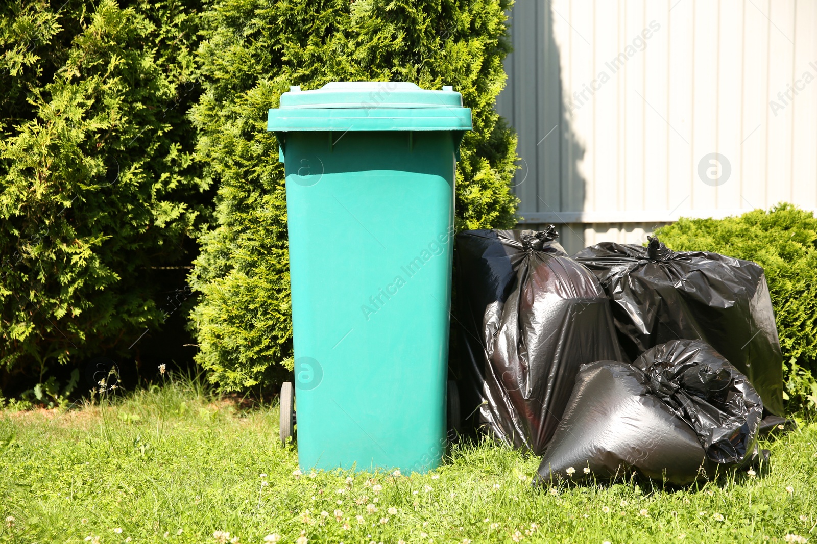 Photo of Trash bags full of garbage near bin outdoors