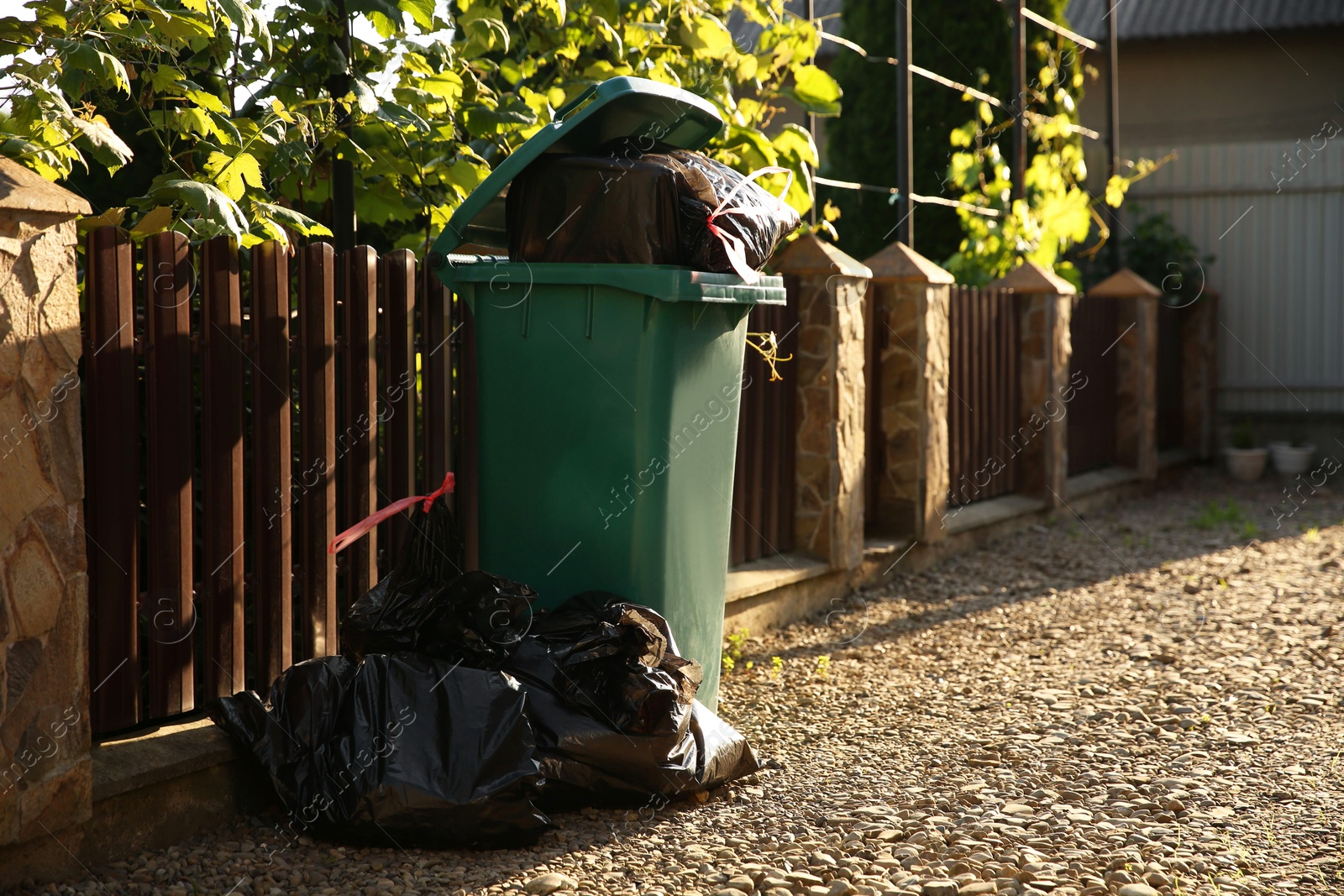 Photo of Trash bags full of garbage near bin outdoors