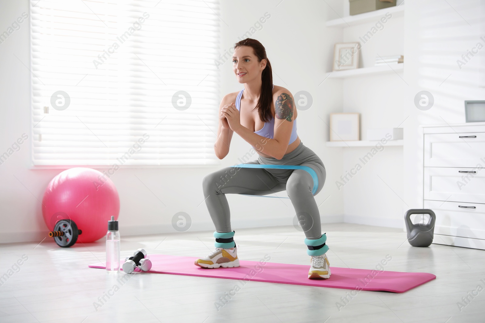 Photo of Woman with ankle weights and elastic band training indoors