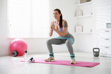 Woman with ankle weights and elastic band training indoors