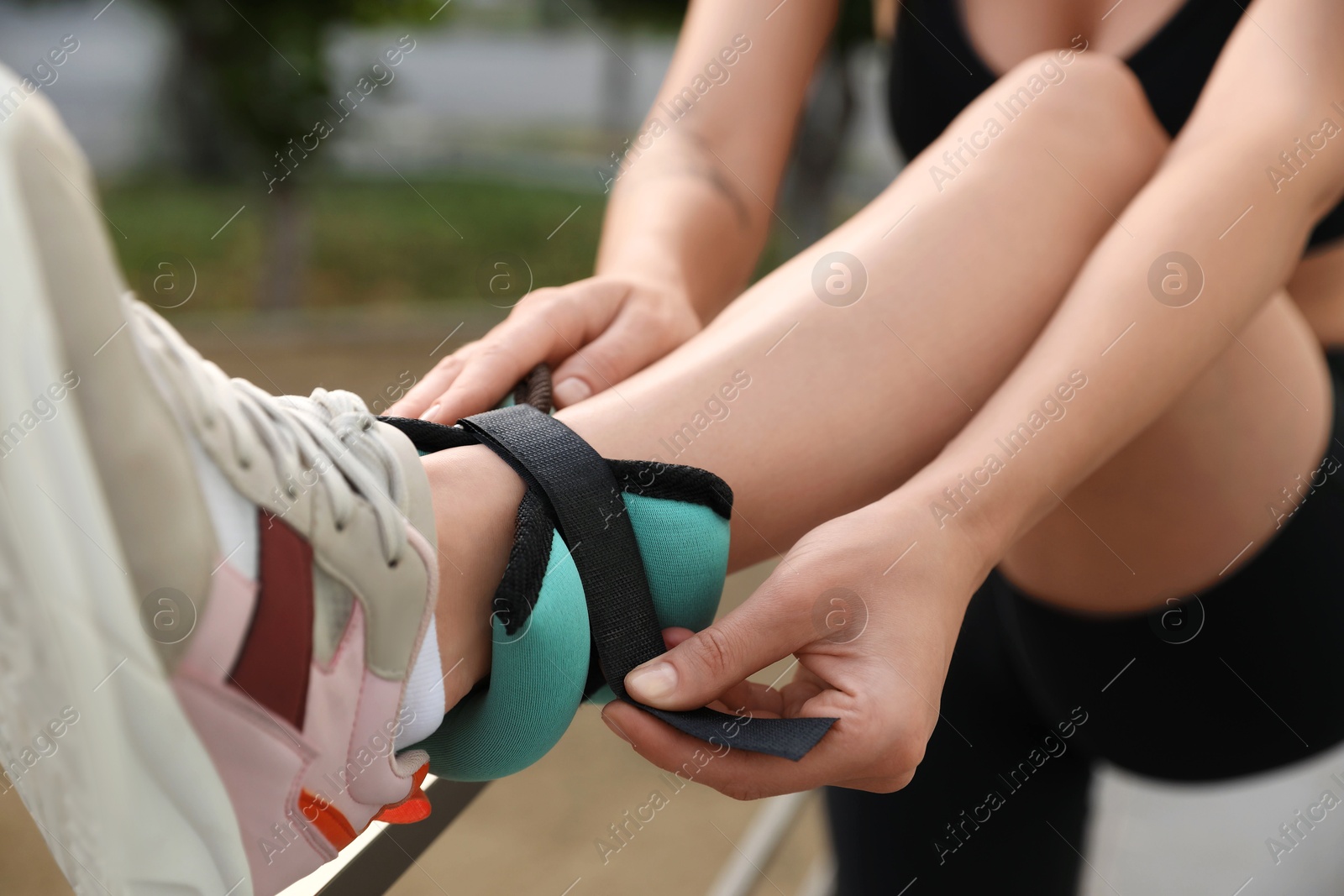 Photo of Woman putting on ankle weight outdoors, closeup