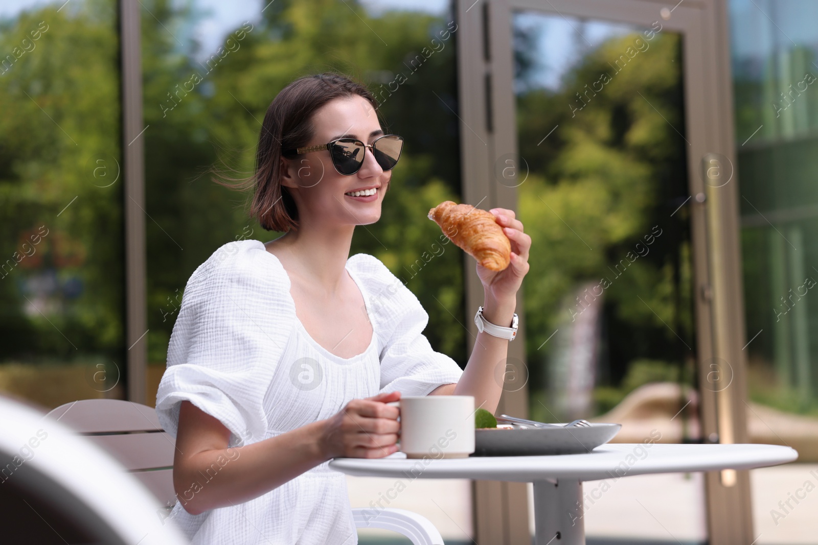 Photo of Happy woman having tasty breakfast in outdoor cafe