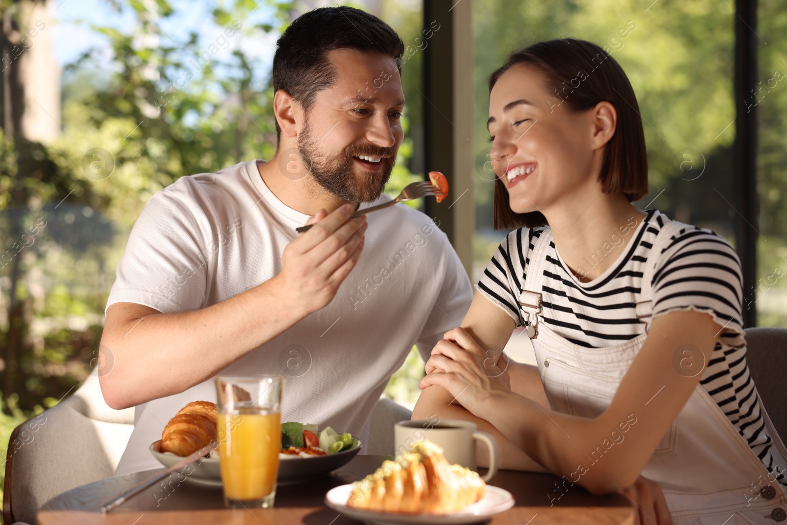 Photo of Happy couple having tasty breakfast in cafe