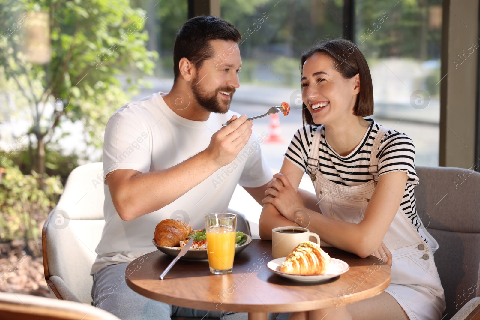 Photo of Happy couple having tasty breakfast in cafe