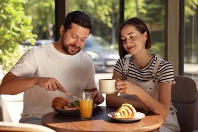 Happy couple having tasty breakfast in cafe