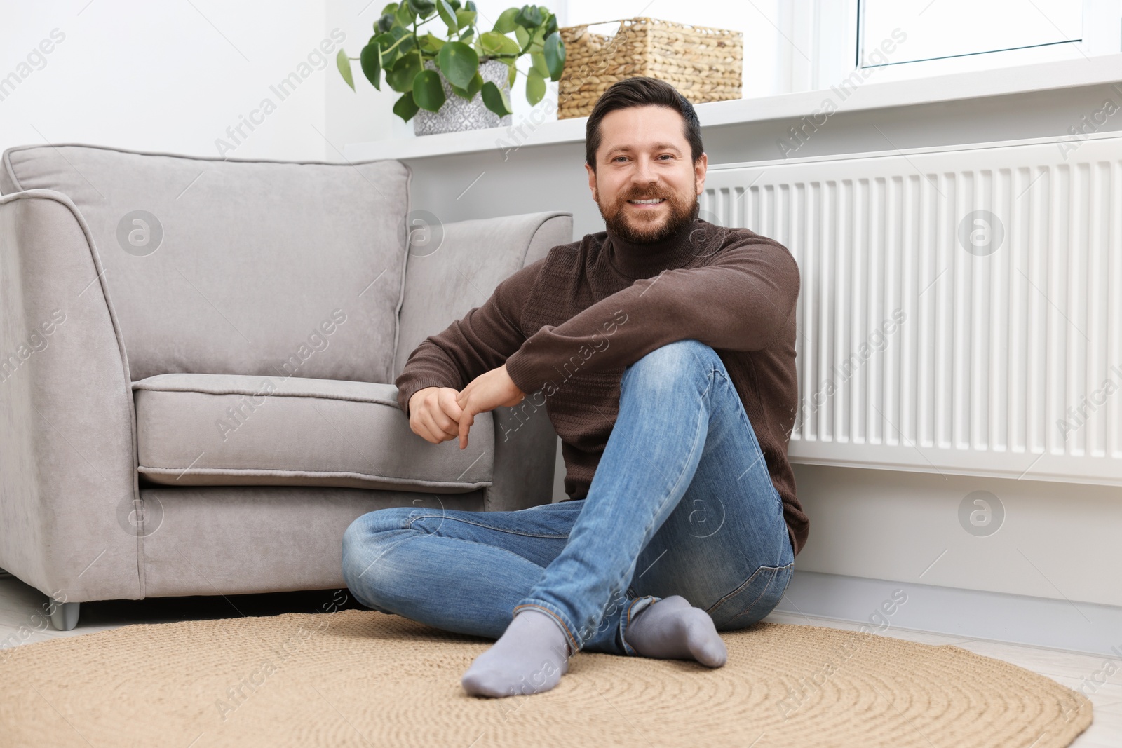 Photo of Happy man near heating radiator at home