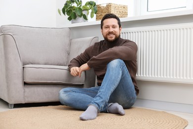 Happy man near heating radiator at home